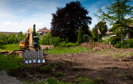 Grundstück mit Garten im Hintergrund und Bagger für Spatenstich