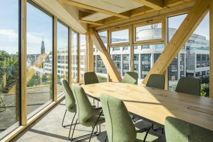 Salle de conférence avec poteaux en bois et larges fenêtres à cadre en bois allant du sol au plafond